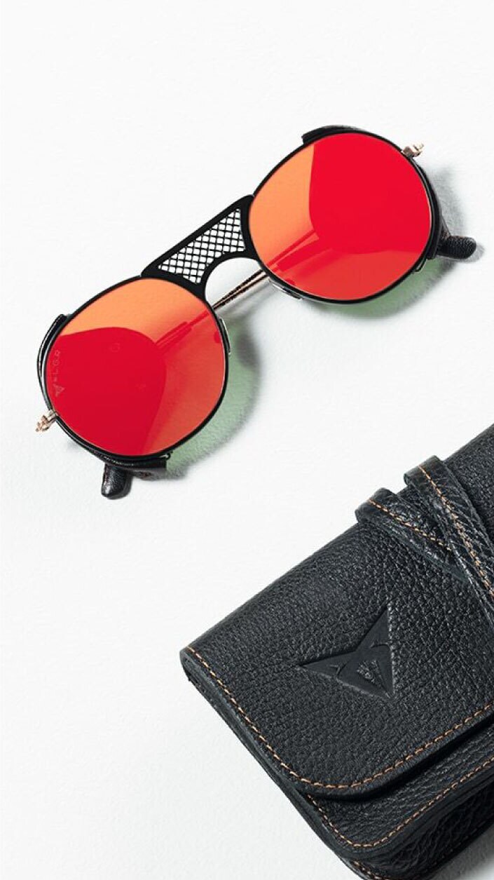 A woman in a light green jumpsuit and dark sneakers appearing to float in a seated position on a city street at night, with a modern glass building in the background.