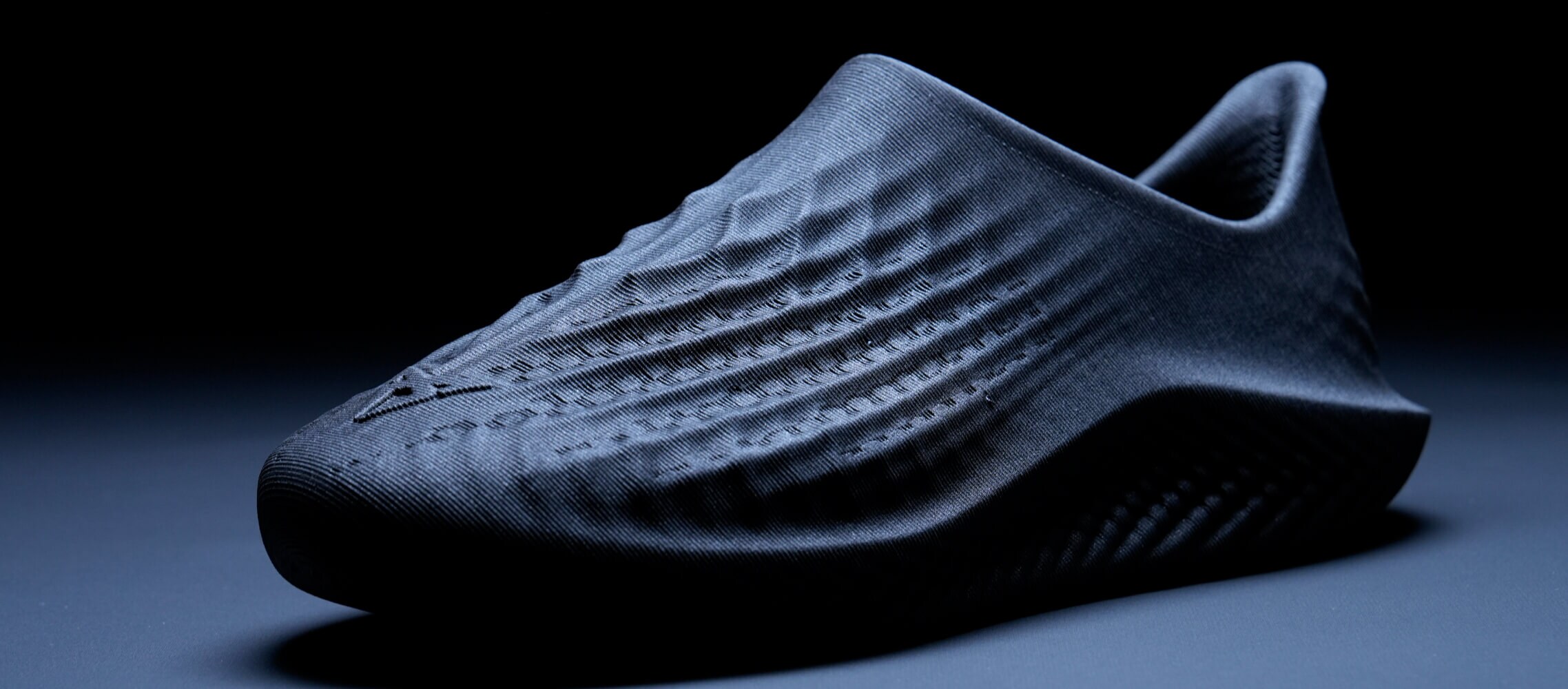 A close-up shot of a dark, textured shoe with a focus on the texture and form.